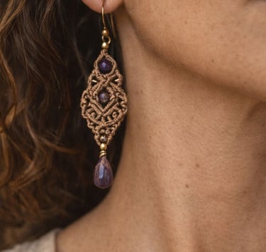 Aretes macramé hechos a mano con piedras de amatista morada usados por una mujer.