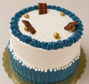 pastel con decoraciones de betun blanco con azul y unas pequeñas perlas doradas y chocolate