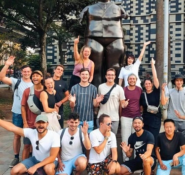 A group of happy travelers posing for a photo in front of the famous Botero statue in Medellin, Colombia.