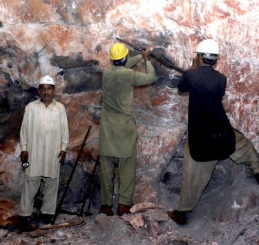 Workers extracting large pink salt blocks at a mining site, preparing them for processing