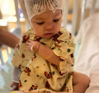 Young child in hospital gown holding book โ inspiration for Delilah character