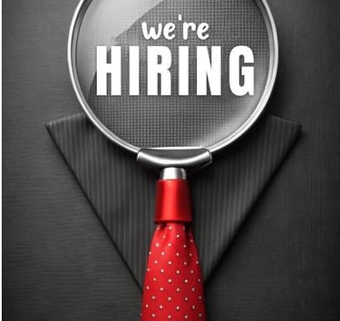 a we're hiring magnifying glass in front a black suit