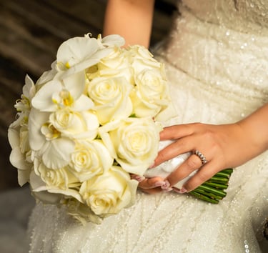 Bride holding a bouquet of white roses with her wedding ring visible, captures by Fred Art Studio