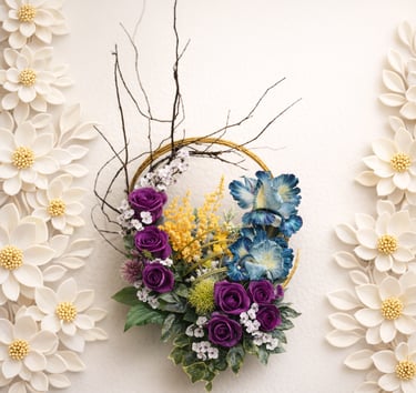 Elegant floral wreath with purple roses and blue flowers on a white wall with paper flower decor.