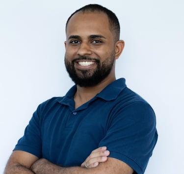 Foto do autor da matéria Igor Souza, sorrindo, com os braços cruzados, blusa polo azul escuro e pare