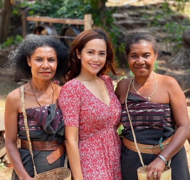 a woman standing in between two tribes women wearing traditional clothes   