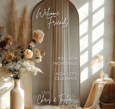 Custom arched wedding mirror sign with floral arrangements and a warm boho reception aesthetic.