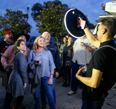 A group of friends posing for a photo with a portable ring light photo booth at an outdoor evening event.