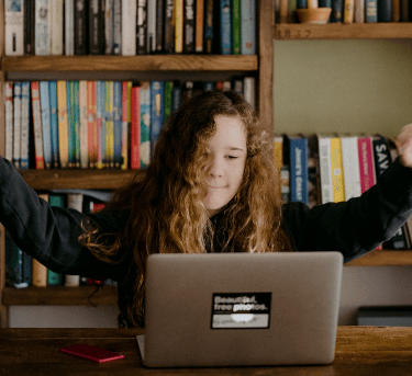 Young Gil with arms raised in celebration at a laptop