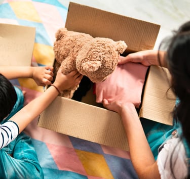 une femme maman et un enfant petit garçon emballe dans un carton un ours en peluche