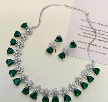 Elegant silver necklace and matching earrings set featuring green emerald-cut stones and cubic zirconia floral accents.