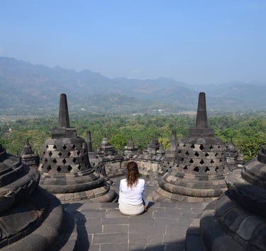 a woman sitting on a stone wall in a temple