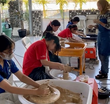 a group of students shaping out clay on pottery wheels