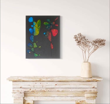 Toile abstraite bleu vert et rouge sur fond noir exposée dans un décor