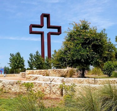 The empty cross standing above green trees