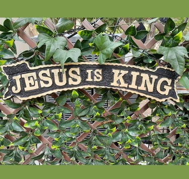 Wood-carved sign reading “Jesus is King.”