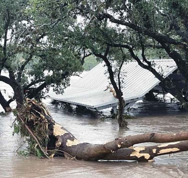 Floodwater covering a park, rising above the roofs of metal picnic shelters.