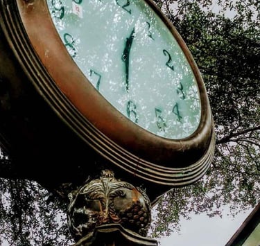 Large clock showing 12:30 with trees reflected in glass