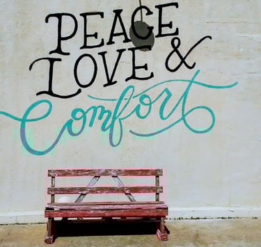 Peace Love and Comfort written on wall above red bench