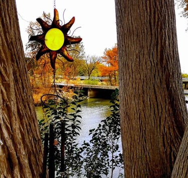 Yellow metal star hanging between two trees, with a river flowing under a bridge