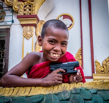 A young novice monk enjoys playing with a toy gun.