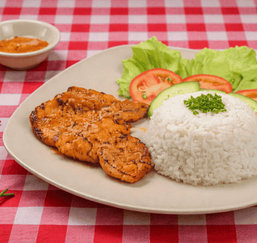 Plato de milanesa con arroz y ensalada sobre una m esa de cuadros rojos con blanco