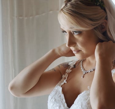 A bride putting on her necklace before her wedding ceremony