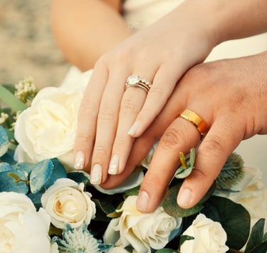 a bride and groom holding hands with their wedding rings