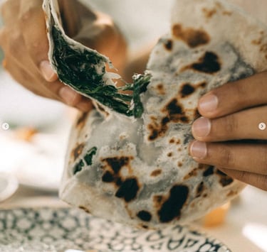 a person holding a piece of cretan mezze in their hand