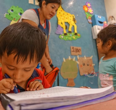 a boy and a girl are sitting at a table at school by Comunidad Nascence