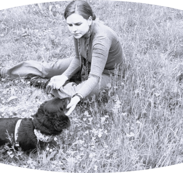 Dog walker in field with dacshund - black and white