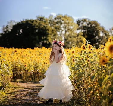 a little girl in a white dress and a flower crown