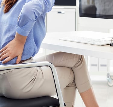 Young woman holding her back, in pain.
