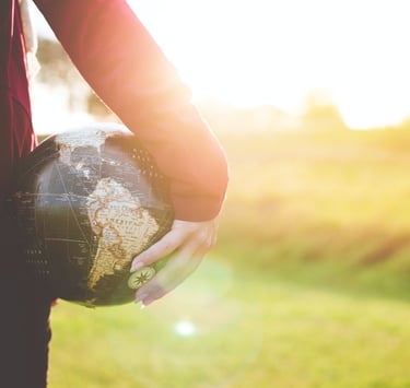 Young person holding a globe in their hand.
