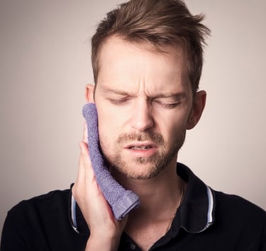 Young man with temporomandibular pain holding his jaw with a towel.