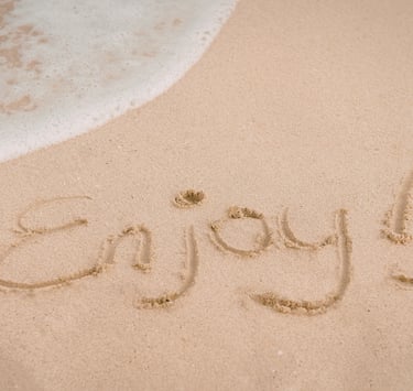 The word ENJOY etched into the sand.