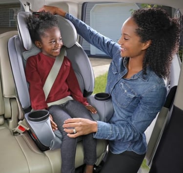Mother putting child in car seat in car
