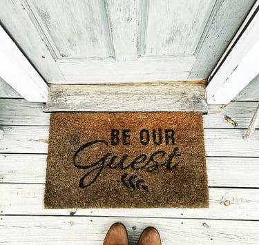doormat at the door with Be Our Guest sign. Market positioning for tourism businesses with Timea