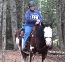 a woman riding a horse in the woods