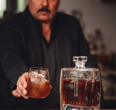 a man in a suit and tie is holding a drink of Luxury Uno Tequila Sinfonia 