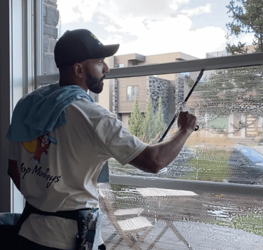 Mop Monkey technician cleaning interior window in Calgary with mop and squeegee 