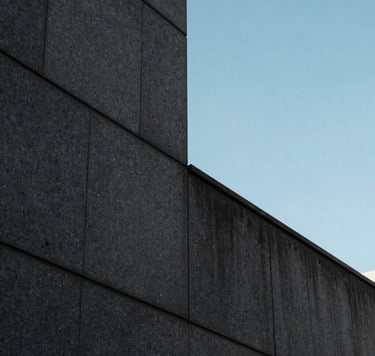 Detailed photography of a modern architectural detail in a Brazilian metropolis, featuring dark gray stone walls and a sharp corner reflecting a serene baby blue sky. The style is sophisticated, minimalist, and very clean.