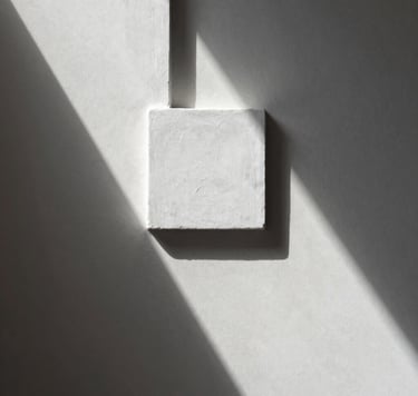 Una fotografía minimalista de un detalle arquitectónico en un estudio español con paredes de color blanco roto y sombras geométricas limpias. Estilo profesional y elegante.