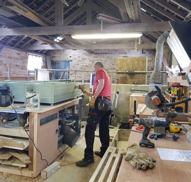 a man in a workshop painting a garden planter