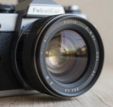 A close-up, artistic shot of a vintage film camera lens reflecting a soft morning light. The composition is clean and premium, focusing on the intricate glass details. The color palette emphasizes sophisticated deep grays (#262626) and soft cream highlights (#F5F0E1), creating a mood of timeless professional artistry.