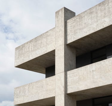 A vertical architectural photograph of a minimalist concrete structure in Olinda. The building features clean lines and sharp geometries against a bright sky. The color palette is dominated by soft off-white and charcoal black accents, with harsh shadows emphasizing technical rigor.