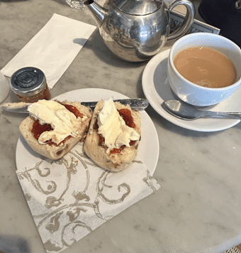 Una experiencia de té inglés con scones, nata espesa, mermelada y té caliente.