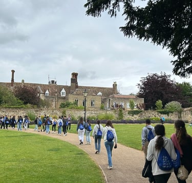 Estudiantes paseando por el jardín de un campus histórico con edificios de piedra