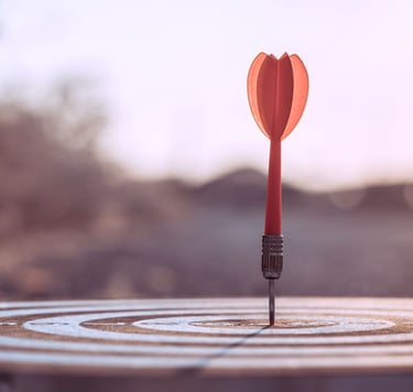 A single red dart hitting the bullseye on a target, representing business success and goals.
