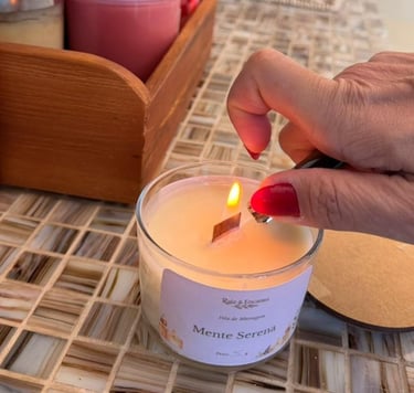Pessoa acendendo uma vela de massagem artesanal da Raiz & Encanto com pavio de madeira.